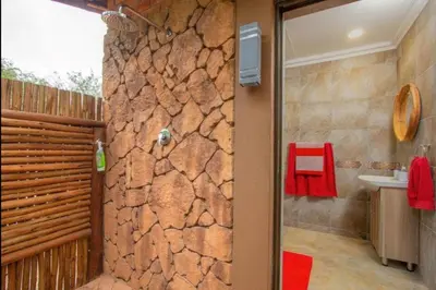a bathroom with a shower with a stone wall at Kaya KaBush in Marloth Park