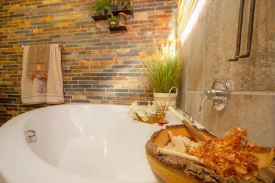 a bathroom with a white tub and a brick wall at Kaya KaBush in Marloth Park