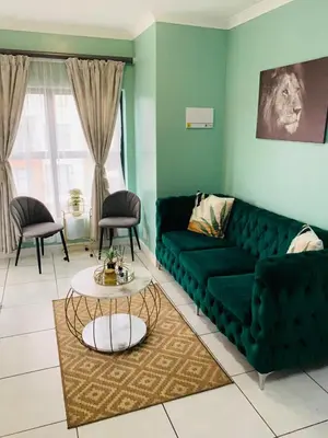 a living room with a green couch and a table at The blyde-Luxury one bedroom apartment in Pretoria