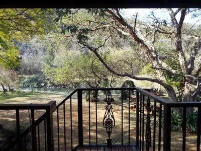 a black iron gate with a view of a park at Aloes Country Inn in Waterval Boven