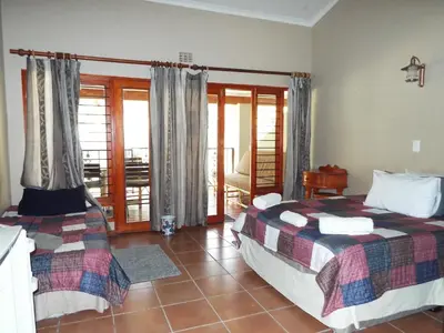 a bedroom with two beds and a balcony at Aloes Country Inn in Waterval Boven