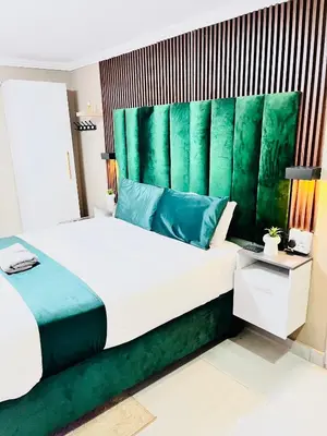 a bedroom with a large bed with a green headboard at Executive Galaxy Guest House Nkowankowa in Nkowakowa