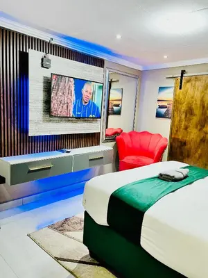 a bedroom with a bed and a tv on a wall at Executive Galaxy Guest House Nkowankowa in Nkowakowa