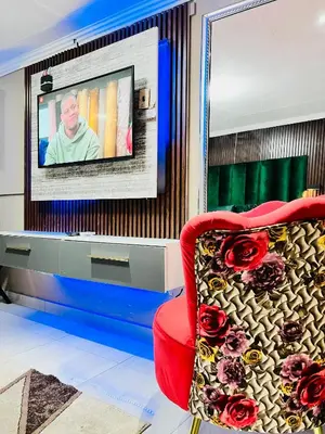 a living room with a red chair and a tv at Executive Galaxy Guest House Nkowankowa in Nkowakowa