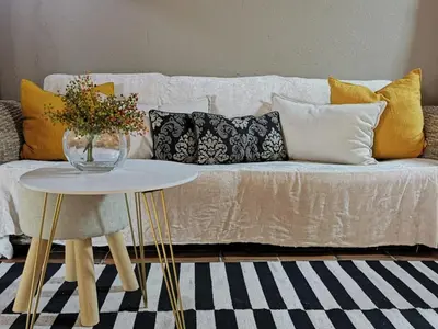 a living room with a couch with pillows and a table at The Homestay in Nelspruit