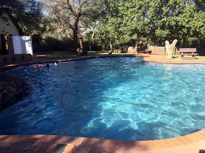 a large pool with blue water in a yard at Kruger Yebo Safari Tents-Stay Inside Kruger in Skukuza