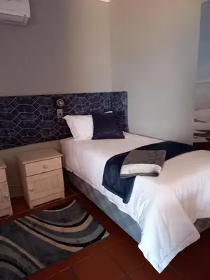 a bedroom with two beds and a rug at Beit-El BnB in Polokwane