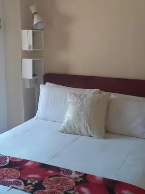 a bed with white sheets and pillows in a room at Beit-El BnB in Polokwane