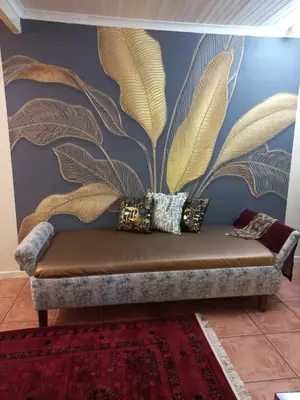 a couch in a room with a wall with a mural at Beit-El BnB in Polokwane