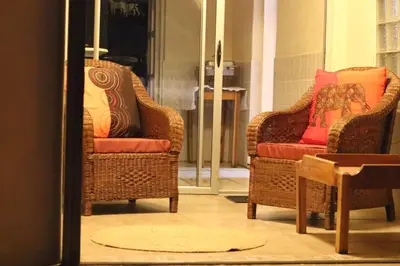 two wicker chairs with red pillows in a room at Beit-El BnB in Polokwane