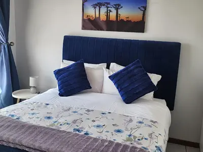 a bed with a blue headboard and two blue pillows at Faerie Glen Heights in Pretoria