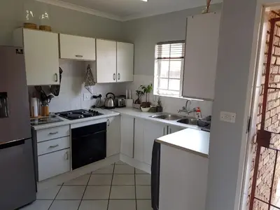 a kitchen with white cabinets and a stove top oven at Faerie Glen Heights in Pretoria