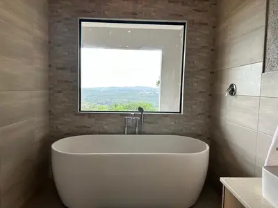 a white bath tub in a bathroom with a window at Hazyview Accommodation, Bon Repose Cottages 3&4 in Hazyview