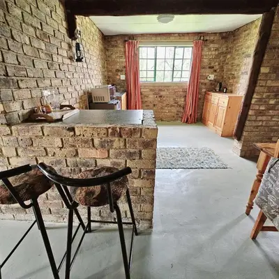a room with a brick wall and a table and a chair at Villa Dachie in Rayton