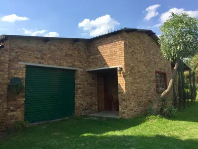 a brick house with a green garage at Villa Dachie in Rayton