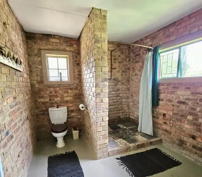 a brick walled bathroom with a toilet and a shower at Villa Dachie in Rayton