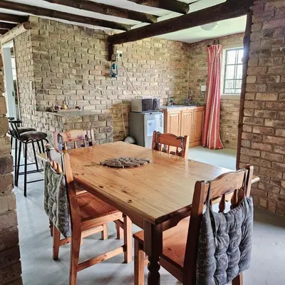 a dining room with a wooden table and chairs at Villa Dachie in Rayton