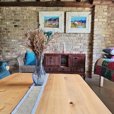 a living room with a table and a brick wall at Villa Dachie in Rayton