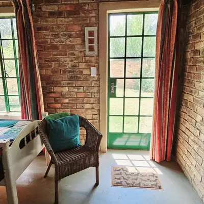 a room with a chair and a brick wall at Villa Dachie in Rayton