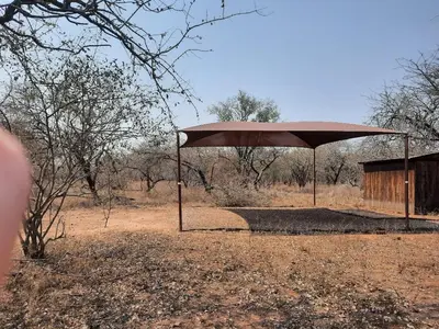 a large umbrella in the middle of a field at Habibi Holiday Home in Marloth Park