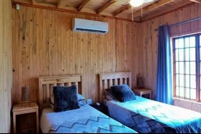 a bedroom with two beds in a wooden wall at Habibi Holiday Home in Marloth Park