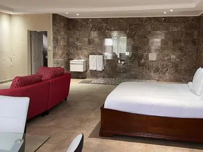 a bedroom with a large bed and a red couch at THE BRIDGE BOUTIQUE LODGE in Moletlane