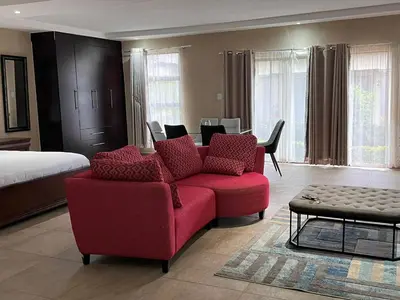 a living room with a red couch and a bed at THE BRIDGE BOUTIQUE LODGE in Moletlane