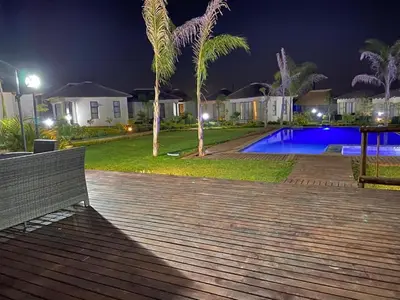 a wooden deck with a bench and a swimming pool at night at THE BRIDGE BOUTIQUE LODGE in Moletlane