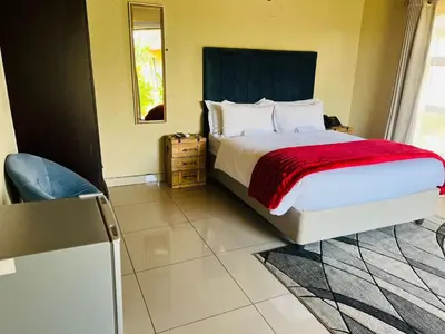 a bedroom with a bed with a red blanket at THE BRIDGE BOUTIQUE LODGE in Moletlane