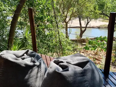 a view of a river from a porch with a blanket at Paradise River Lodge in Hoedspruit