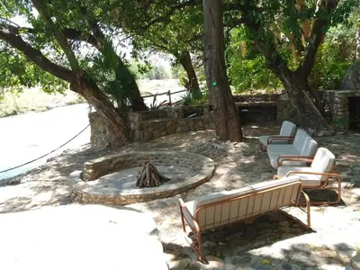 two chairs and a fire pit in a yard with trees at Paradise River Lodge in Hoedspruit