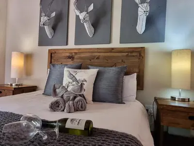 a bedroom with a bed with a bottle of wine at Paradise River Lodge in Hoedspruit
