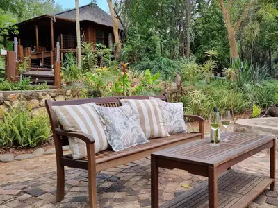 a wooden bench with pillows and a wooden table at Paradise River Lodge in Hoedspruit