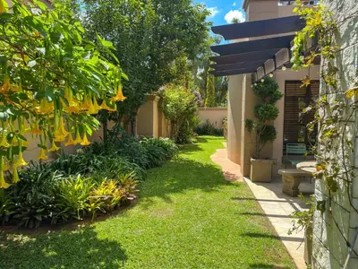 a garden with green grass and a building at Villa Toledo - Luxurious Mediterranean styled home in Pretoria