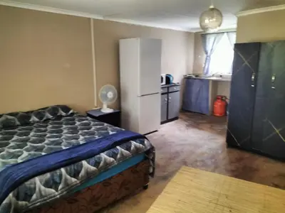 a bedroom with a bed and a kitchen with a refrigerator at BLESSINGS Sleep Over in Mokopane