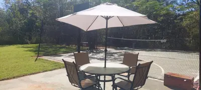 a table and chairs with an umbrella on a tennis court at Vulture's View 9 in Hartbeespoort