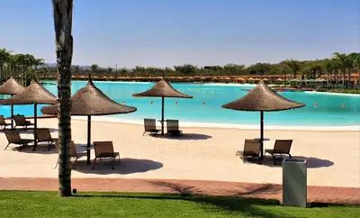 a pool with chairs and umbrellas on a beach at The Blyde Crystal Lagoon Luxurious Apartment in Pretoria
