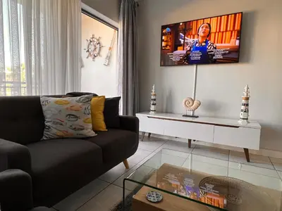 a living room with a couch and a tv on the wall at The Blyde Crystal Lagoon Luxurious Apartment in Pretoria
