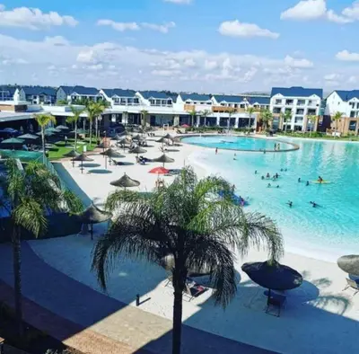 a large swimming pool with palm trees in a resort at The Blyde Crystal Lagoon Luxurious Apartment in Pretoria