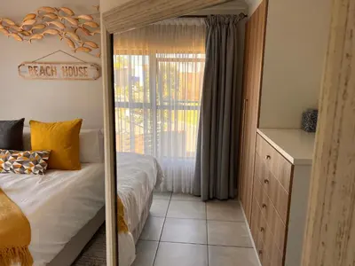 a bedroom with a bed and a dresser and a mirror at The Blyde Crystal Lagoon Luxurious Apartment in Pretoria