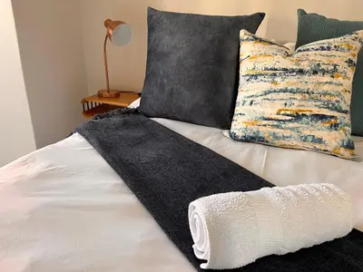 a bed with a black and white blanket and pillows at The Blyde Crystal Lagoon Luxurious Apartment in Pretoria