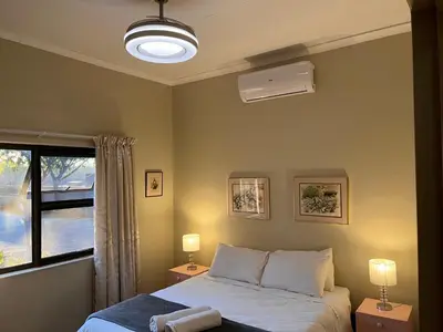 a bedroom with a bed with two lamps and a window at Panache Wildlife Cottage-Self Catering in Hoedspruit