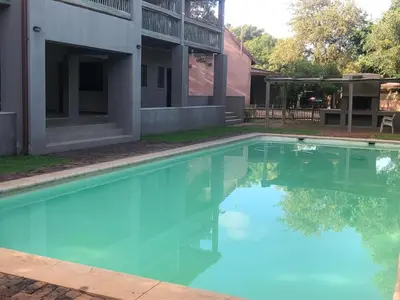 a swimming pool with blue water in front of a building at Panache Wildlife Cottage-Self Catering in Hoedspruit