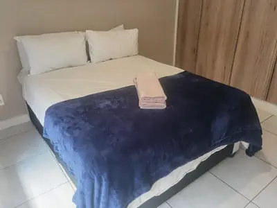 a bed with a blue and white blanket on it at Three Bedroom Apartment At The Blyde in Boschkop