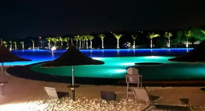 a swimming pool with chairs and umbrellas at night at Three Bedroom Apartment At The Blyde in Boschkop
