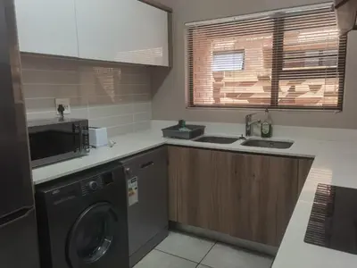a kitchen with a washing machine and a microwave at Three Bedroom Apartment At The Blyde in Boschkop