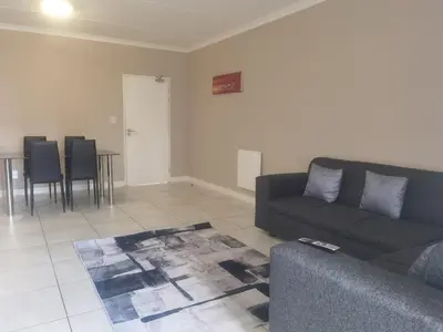 a living room with a couch and a table and chairs at Three Bedroom Apartment At The Blyde in Boschkop