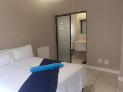 a bedroom with a white bed with a blue towel on it at Three Bedroom Apartment At The Blyde in Boschkop