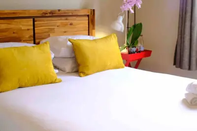 a bedroom with a bed with yellow pillows and a bed sidx sidx at Perfectly located beauty in secure Estate in Sandton