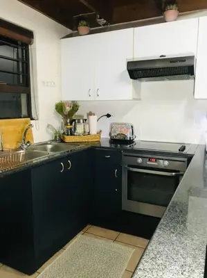 a kitchen with black cabinets and a sink and a stove at Perfectly located beauty in secure Estate in Sandton